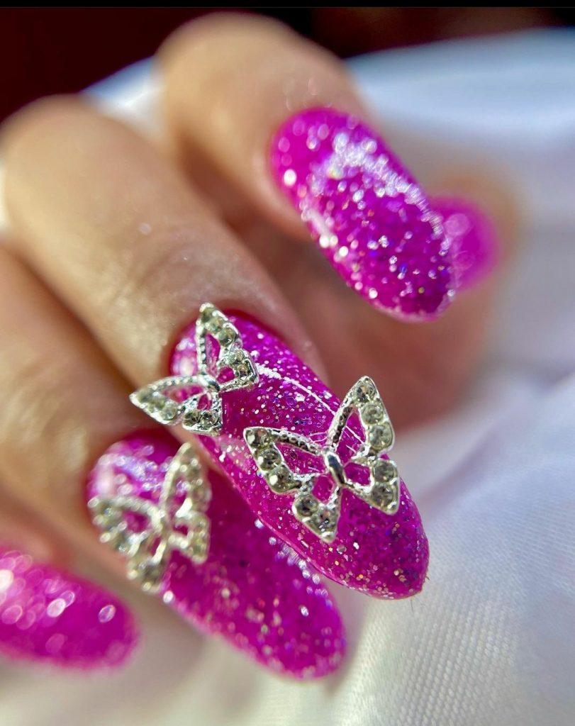 pink glitter nails with butterfly studs 