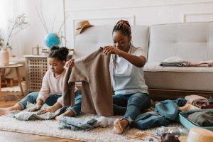 A child learning to fold clothes with mother