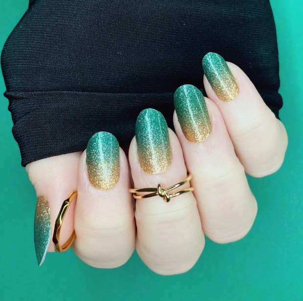 Glittery emerald and gold ombre nails.