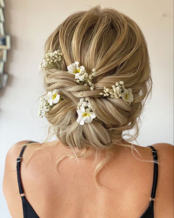 Twisted bridal hairstyle adorned with delicate flowers.