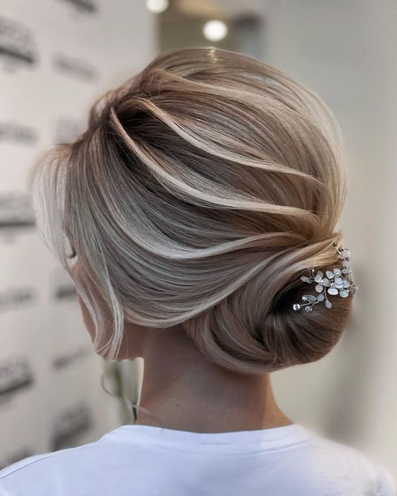 Sleek low bun with a chic hairpiece.