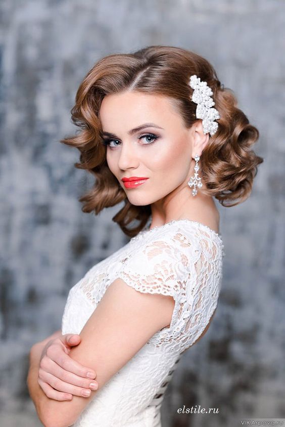 Vintage curly bridal hairstyle with a white hairpiece.