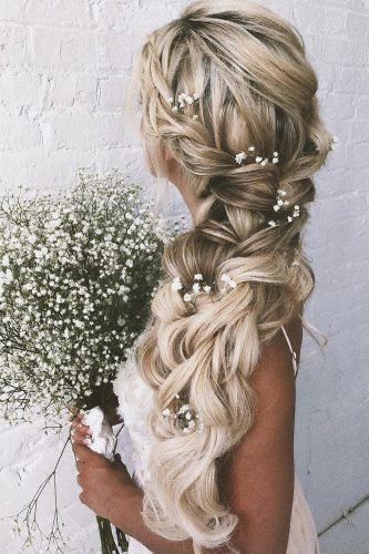 Side swept voluminous braids with white flowers.