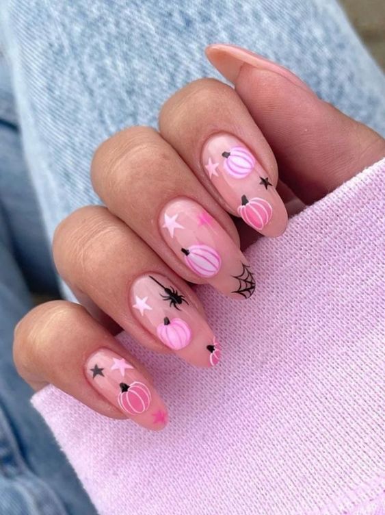 Nude base nails with spider and pink pumpkin motifs.