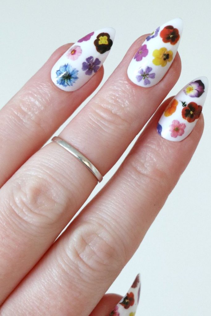 Multicolored flowers on opaque white almond nails.