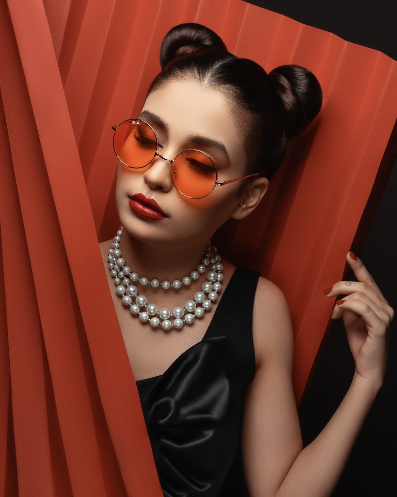 Girl wearing shades and pearl necklace.