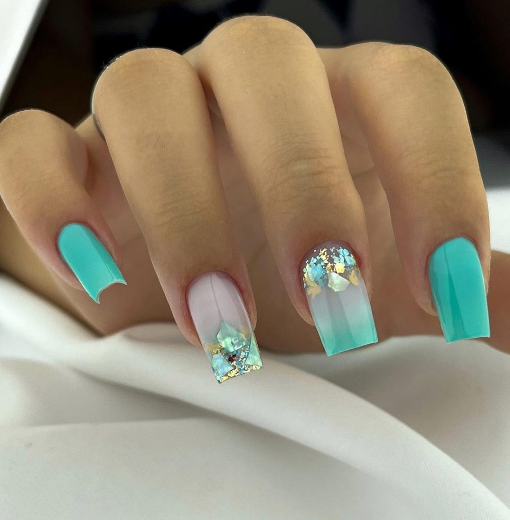 Cloudy white square nails with aqua accents.