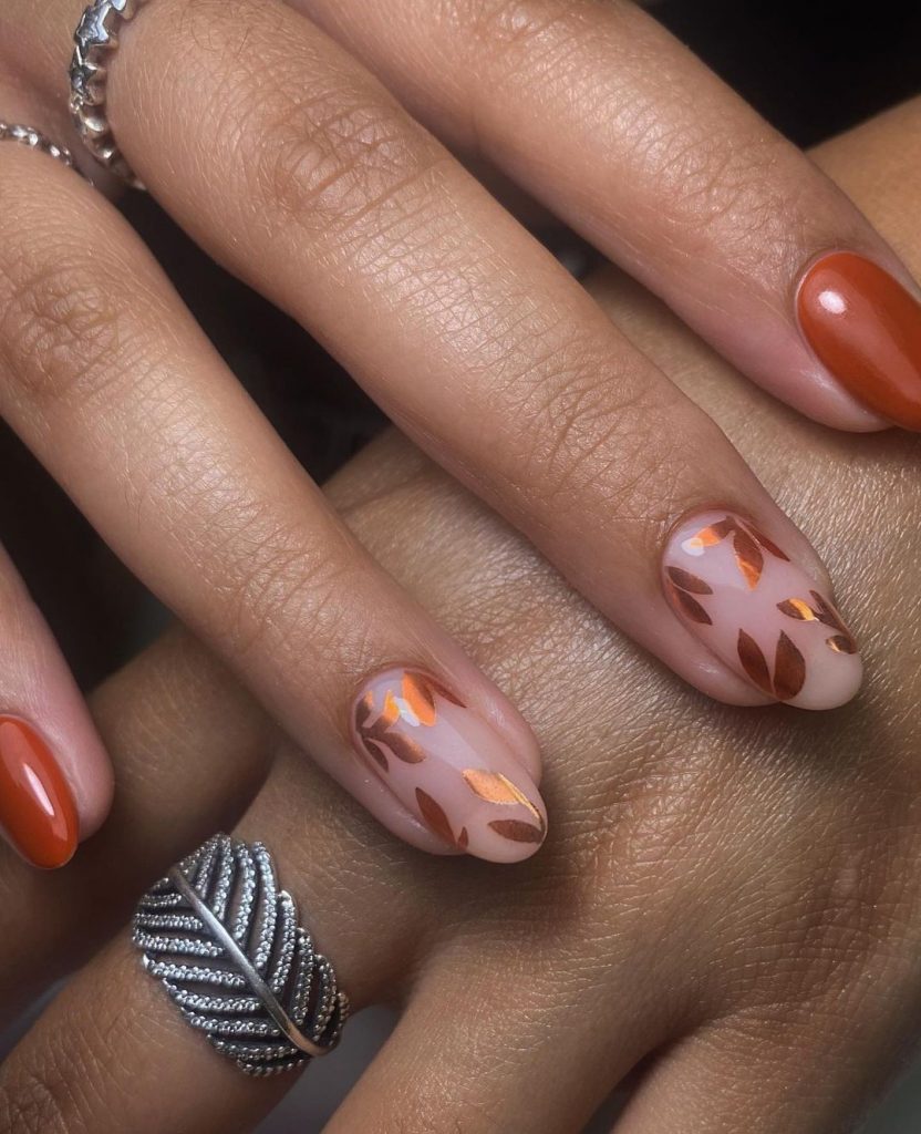 Orange round nails with leaves motif.