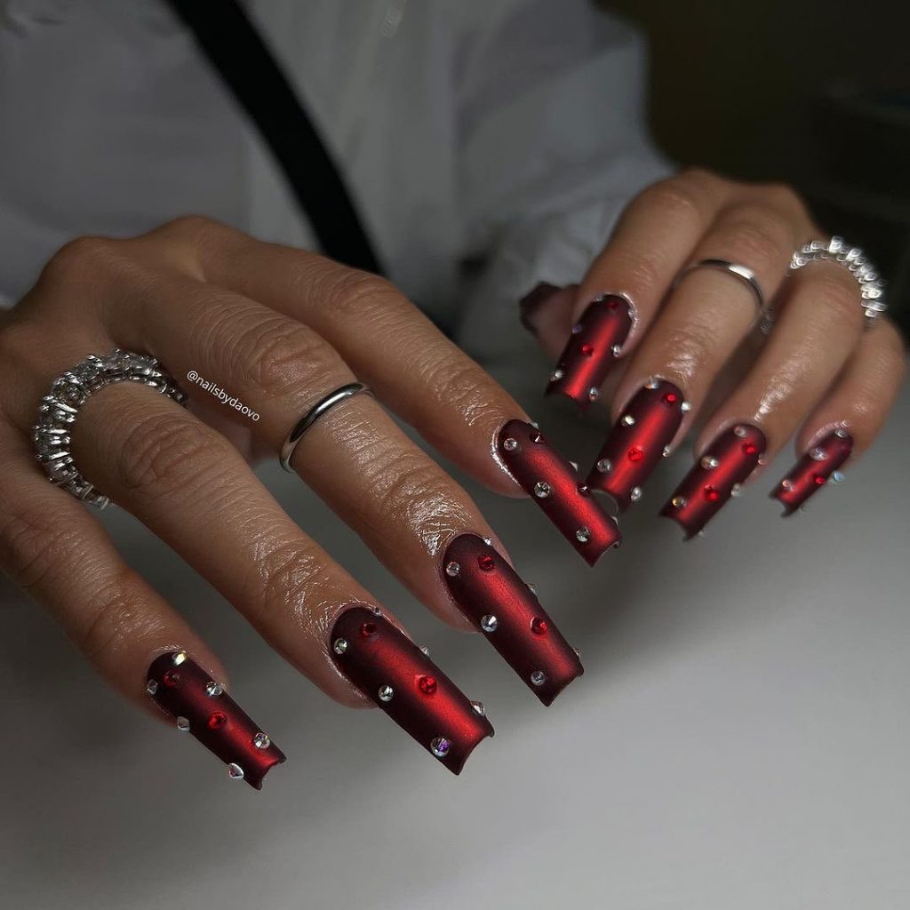 Matte red square nails with embedded stones.