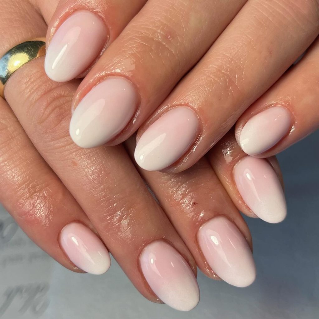 Ombre effect in light nude and white hues on round nude nails.