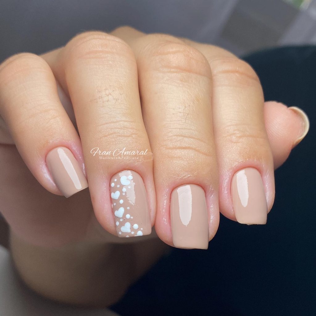 Small square nails with white hearts in a light nude shade.
