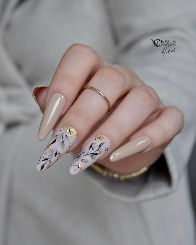 Long rounded taupe nails with a leaf design.