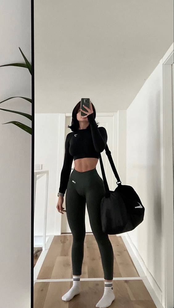 Woman wearing a solid black full-sleeved crop top with high-waisted gym leggings.