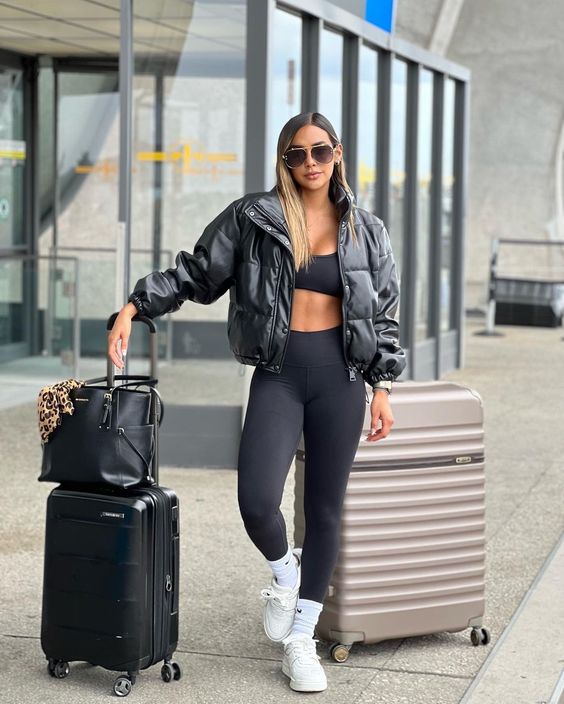 Effortless airport vibe with black bomber jacket, blouse, and leggings.