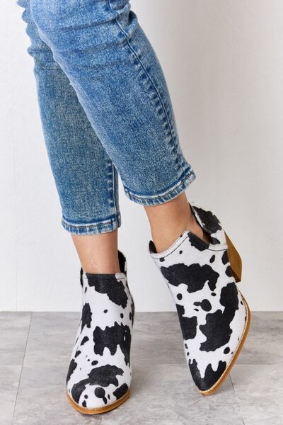 Striking black and white ankle cowboy boots with textured cow print.