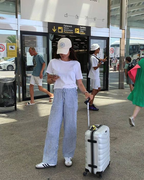 White tee and striped trousers, the epitome of airport comfort.