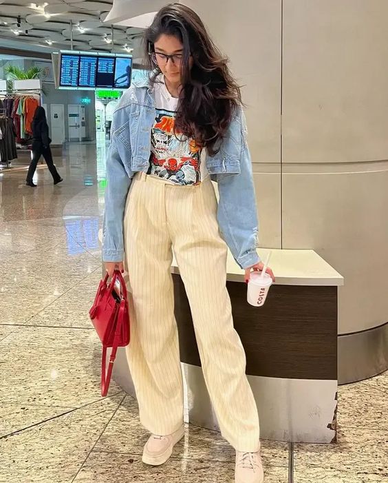 Airport look with a white graphic tee, beige striped trousers and denim jacket.