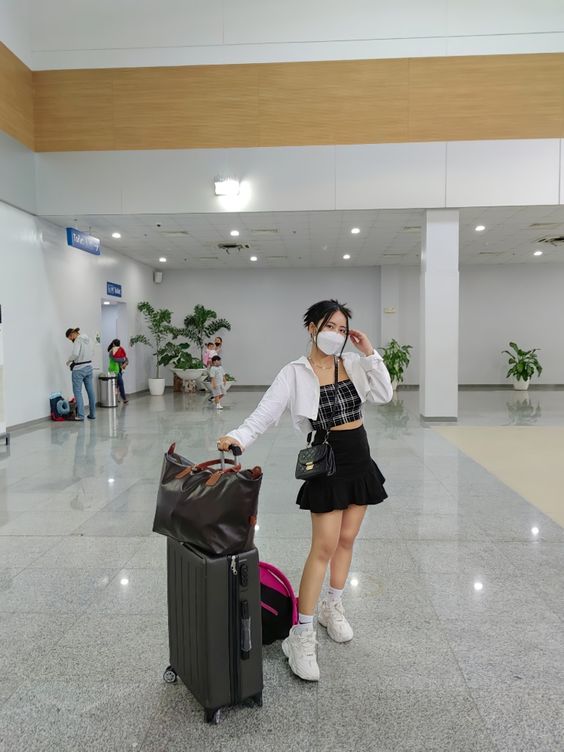 Airport chic with flared mini skirt, crop top and crop white shirt.