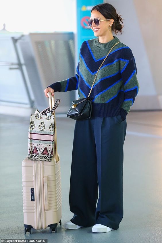 Chunky print sweater and blue trousers for airport-ready fashion.