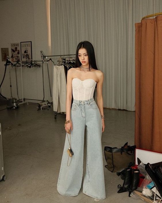White off-the-shoulder corset with flare blue denim trousers.